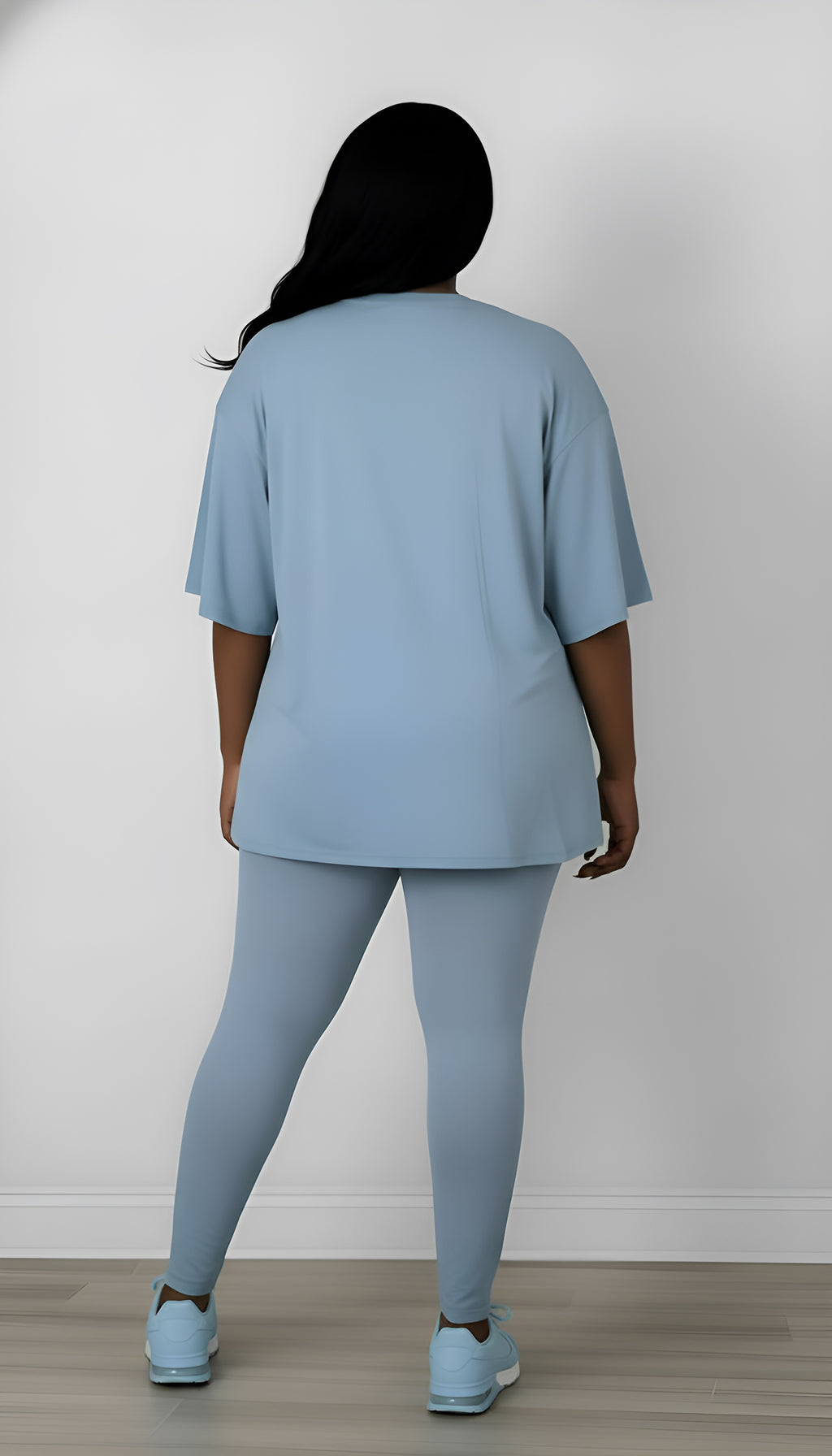 woman wearing a light blue outfit standing against a white wall.