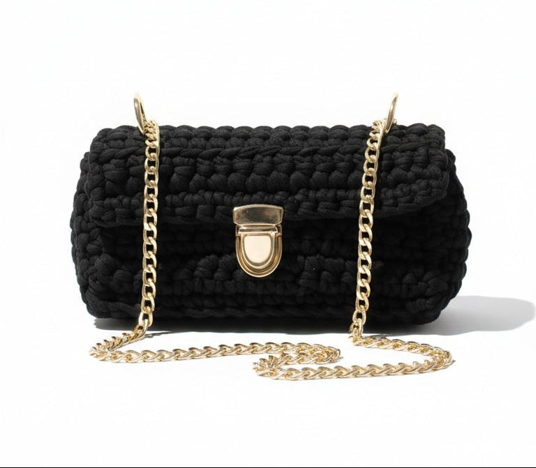Black crocheted handbag with gold chain strap on a white background