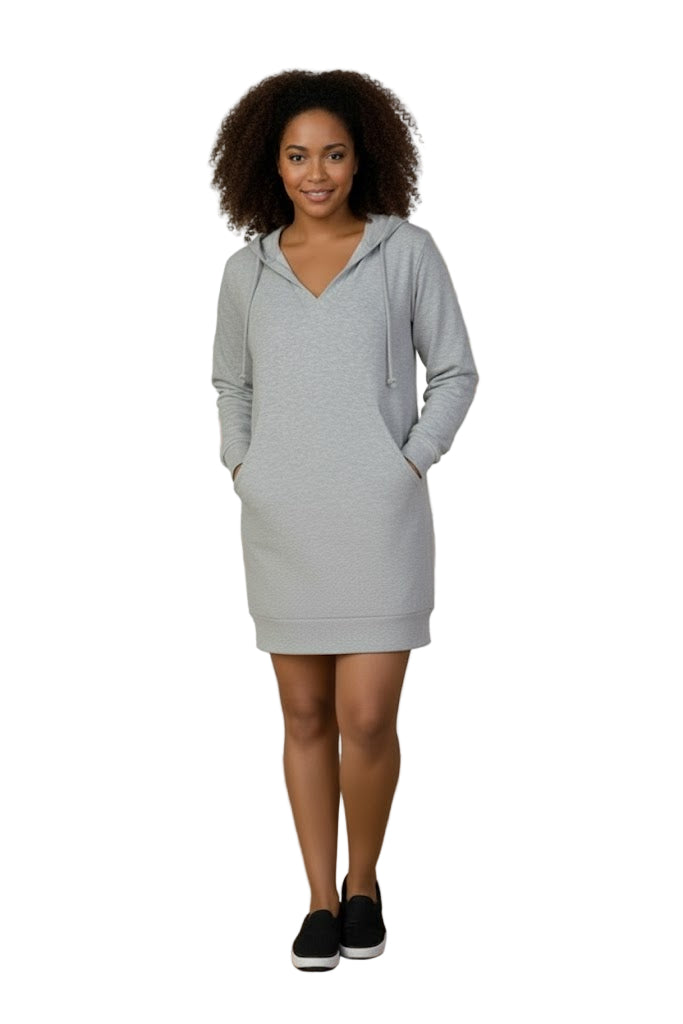 Woman wearing a gray hoodie dress standing in a room with a mirror and desk.