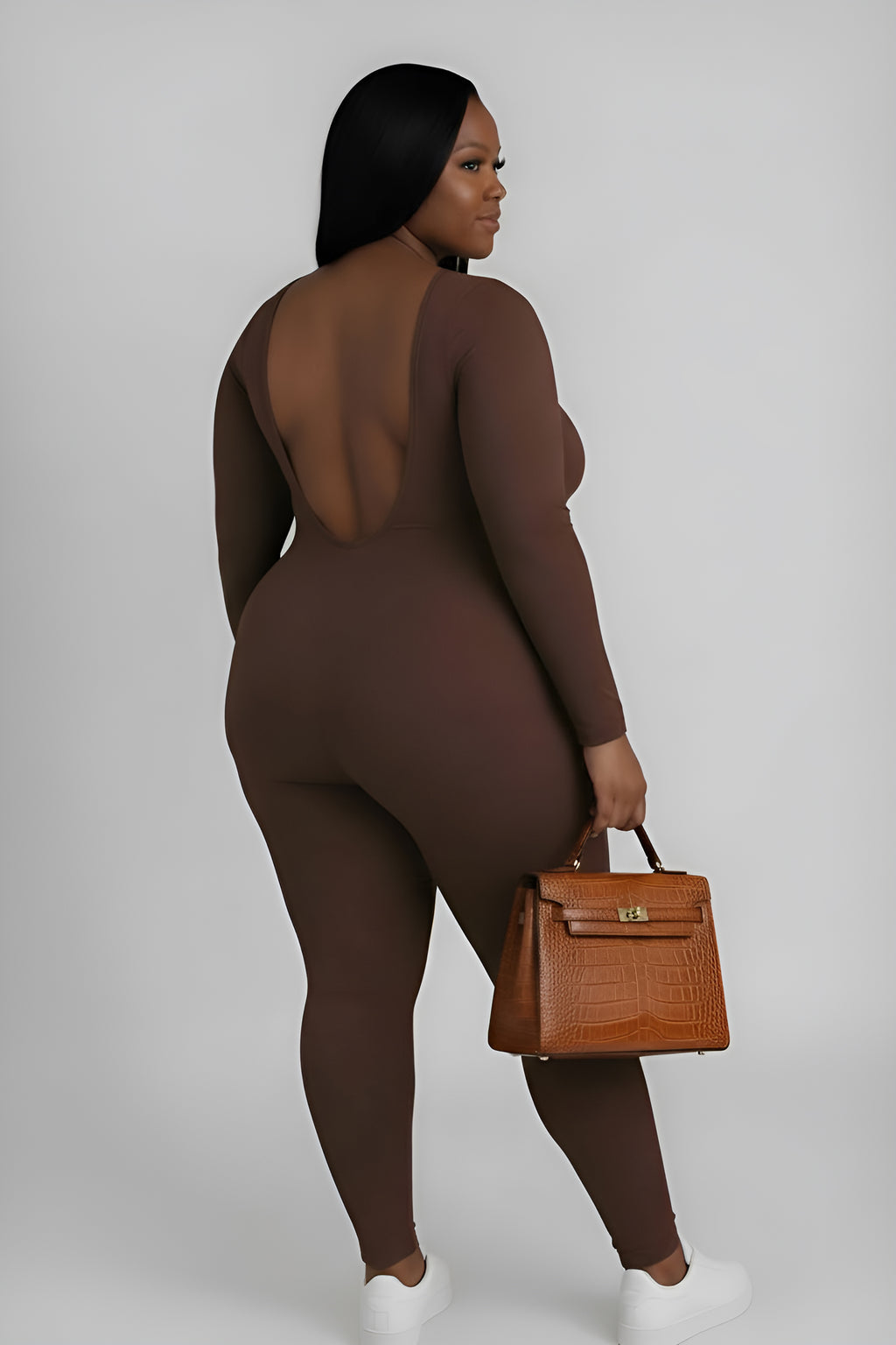 woman wearing a brown outfit holding a tan handbag on a white background