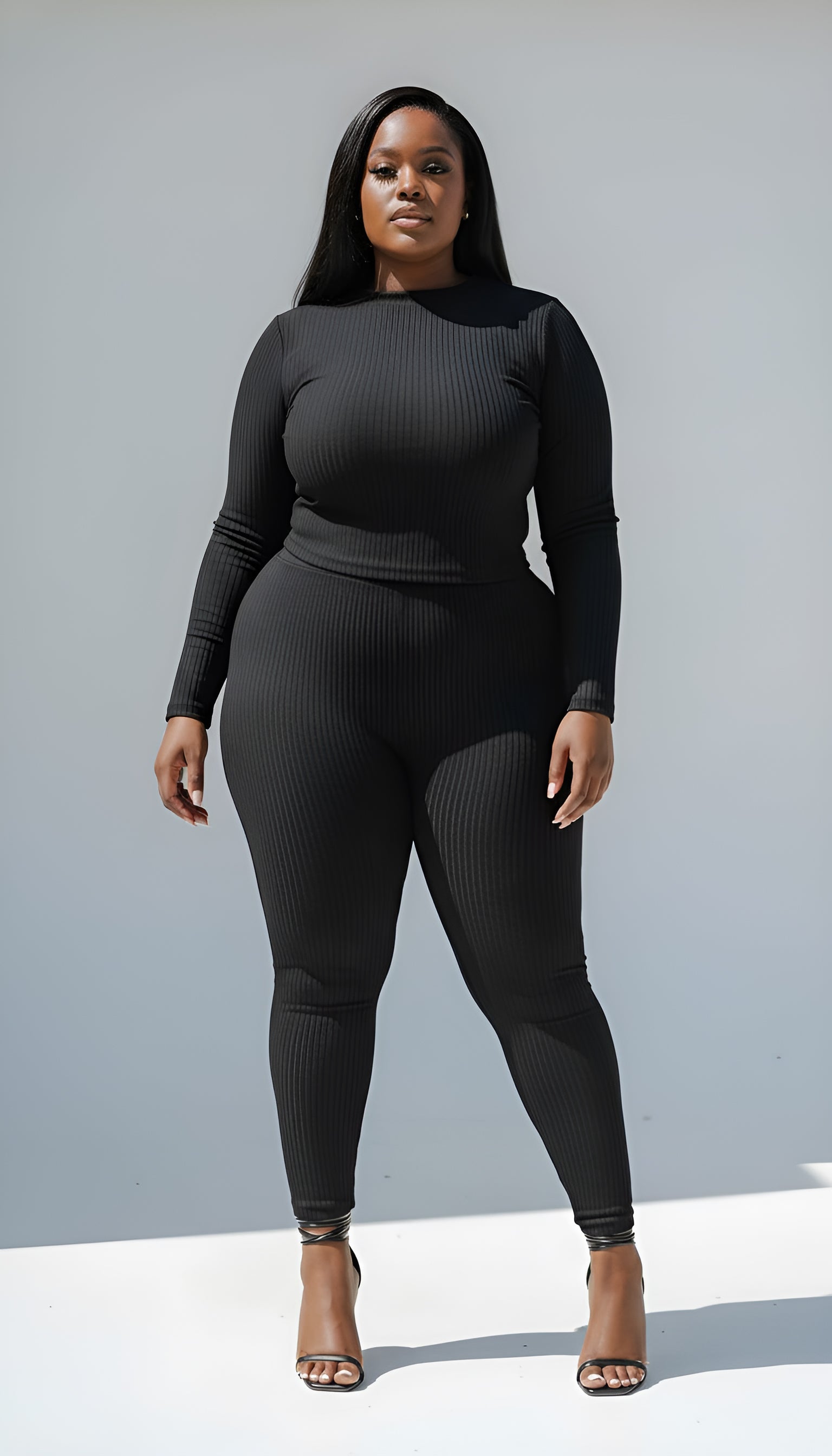 Person wearing a black ribbed outfit against a gray background