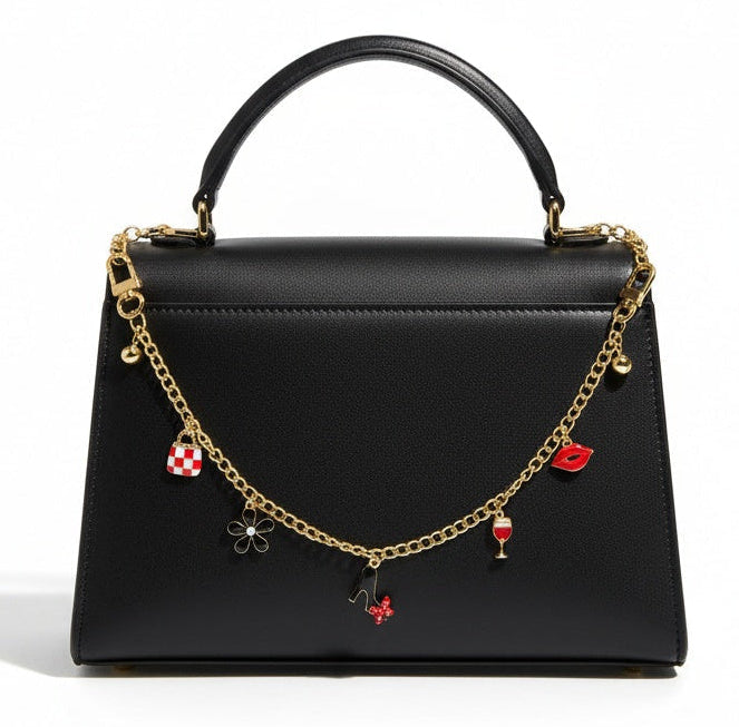Black handbag with gold chain and red heart charms on a white background