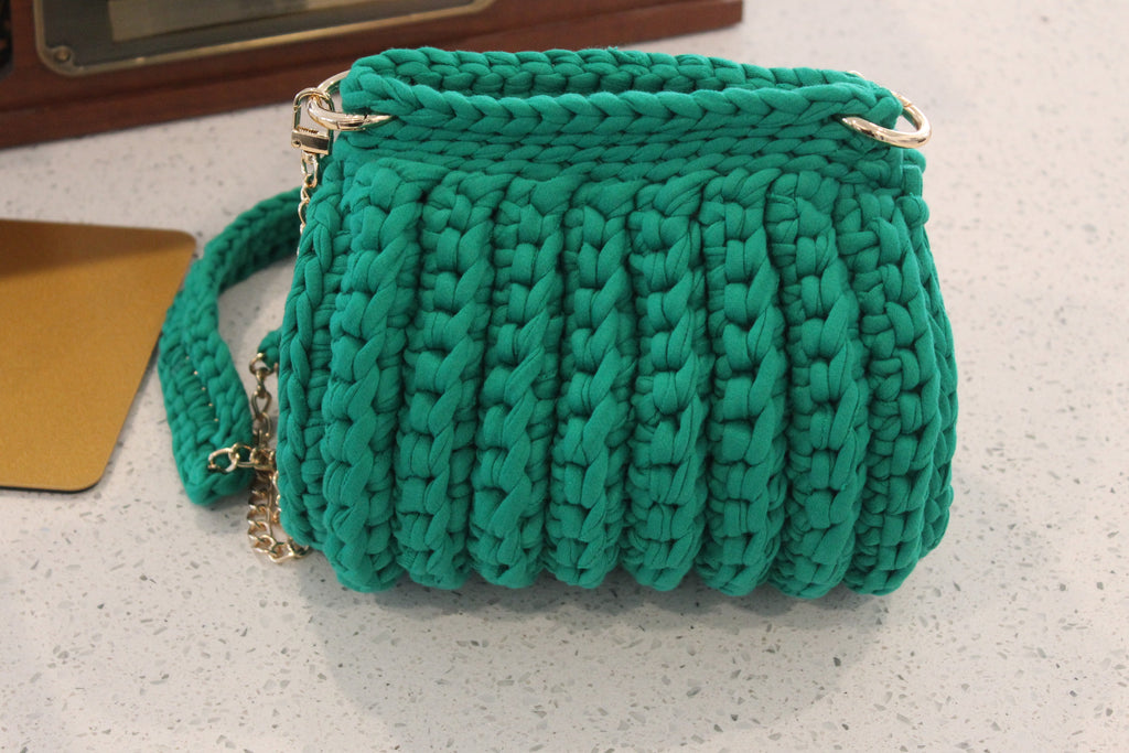 Green handknitted handbag on a light surface