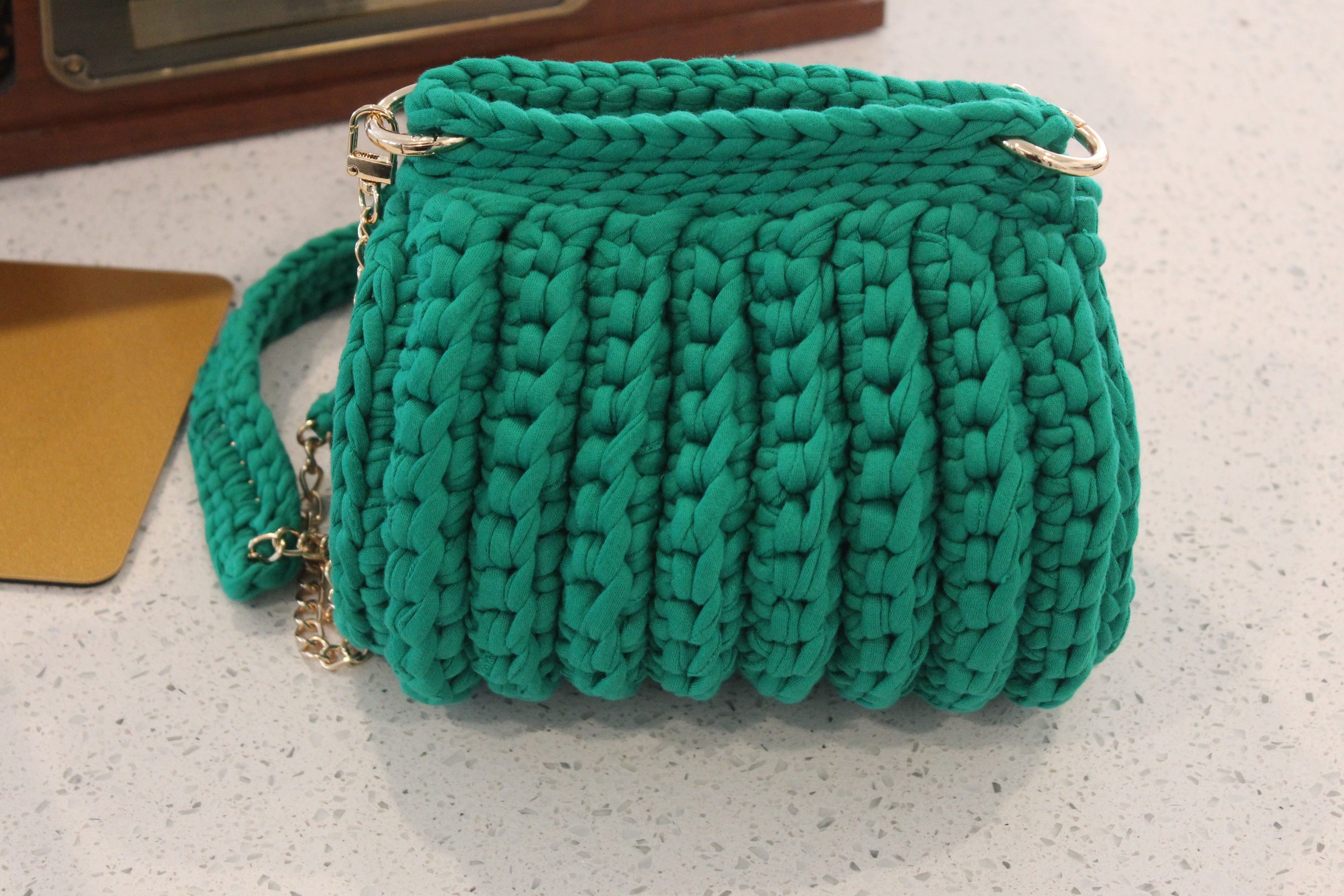 Green handknitted handbag on a light surface