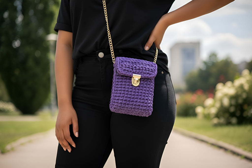 Person wearing a black outfit with a purple hand knitted crocheted bag in an outdoor setting