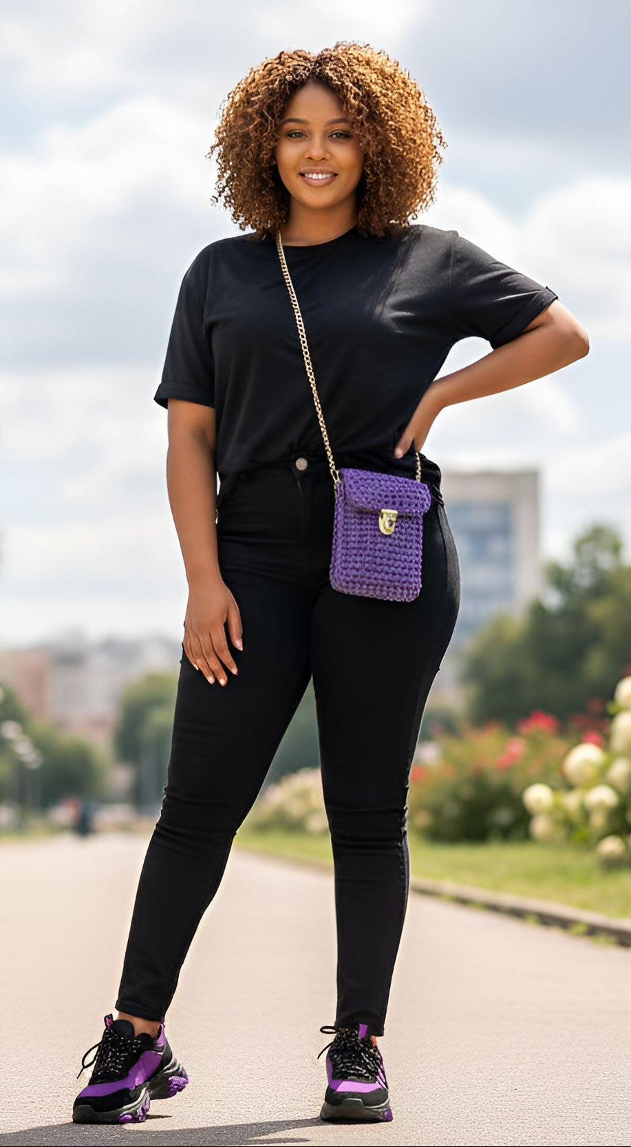 Woman in black outfit with a purple handmade knit handbag standing outdoors