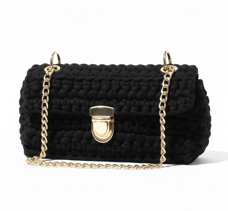 Black textured handbag with gold chain strap on a white background