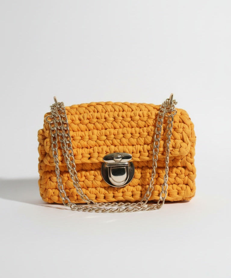 Yellow woven handbag with a chain detail on a white background